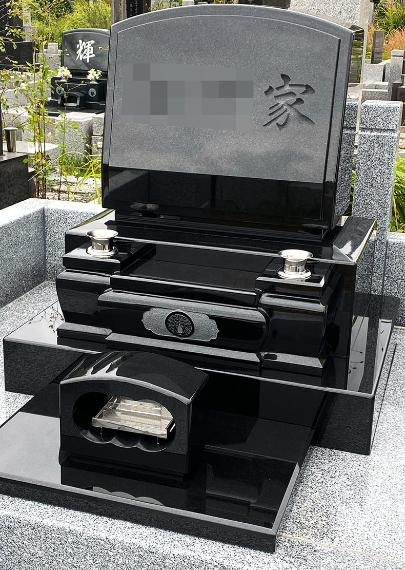 墓石に額だし加工、花立てと一体型の水鉢の中央に家紋を彫刻しています。 正面文字は家名を普通彫りで彫刻しています。