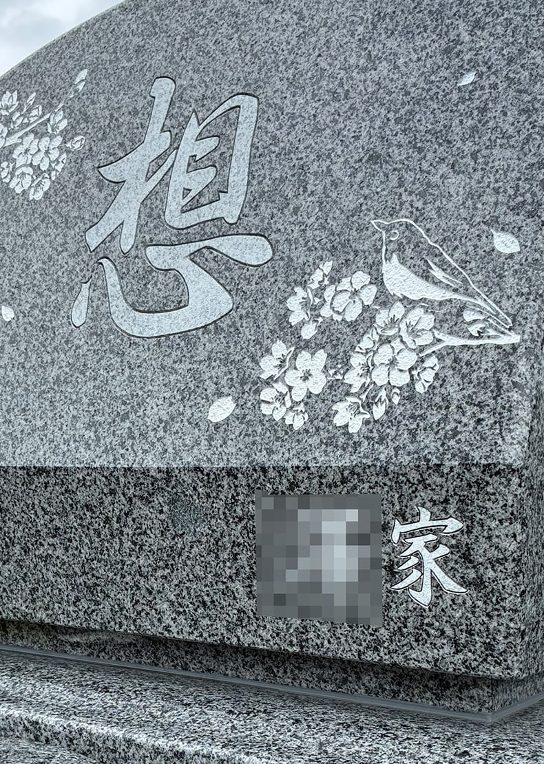 墓石の正面に「想」の文字と桜とメジロのイラスト、 家名を右下に彫刻しています。