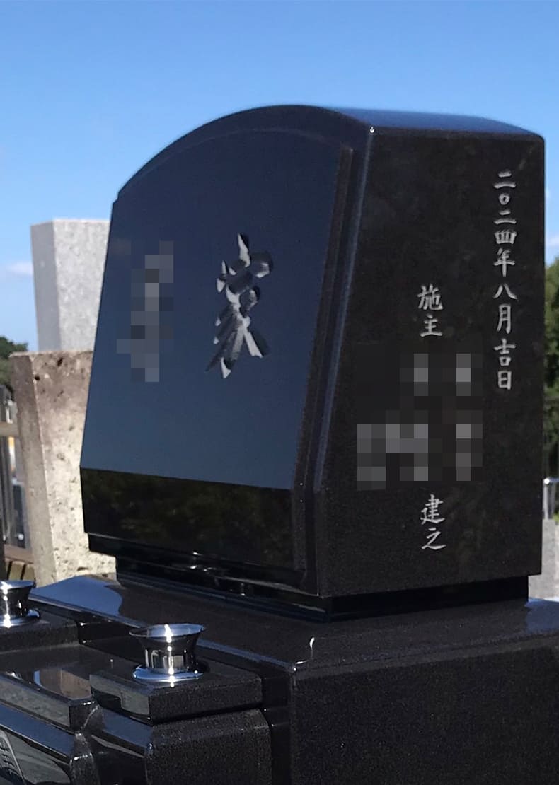 墓石に額だし加工、花立てと一体型の水鉢の中央に家紋を彫刻しています。 正面文字は家名を普通彫りで彫刻しています。